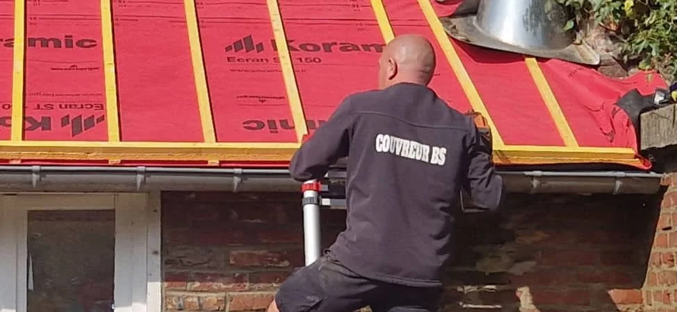 Couvreur BS Couvreur travaillant en sécurité le long de la corniche pour nettoyer la gouttière dans le 77